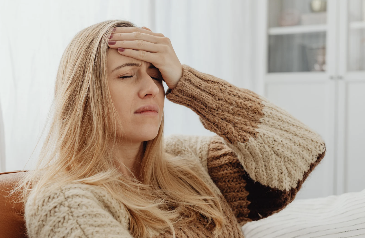 Woman with hand on her forehead, experiencing fatigue