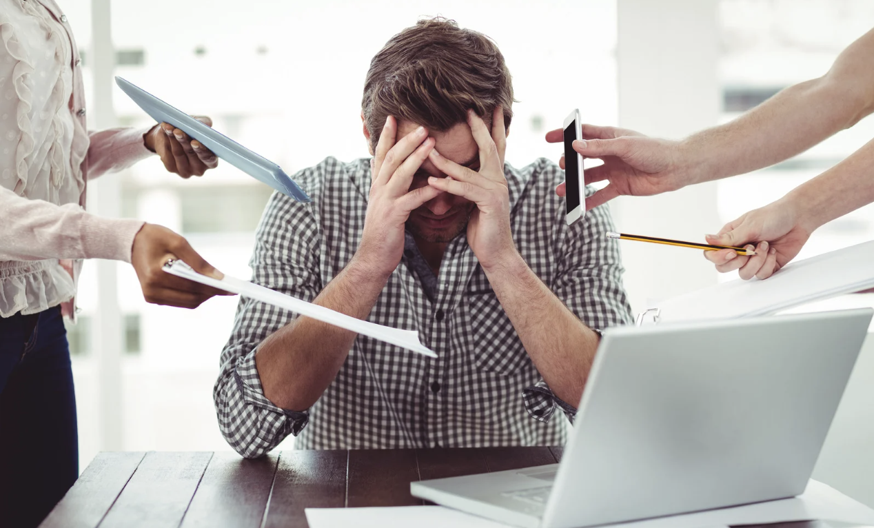 Stressed man overwhelmed by work demands, symbolizing impaired executive function which can be influenced by poor gut health and chronic inflammation.