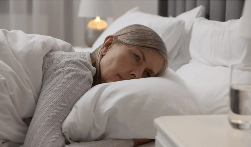 Perimenopausal woman lying awake in bed, reflecting sleep disturbances linked to hormonal and immune dysregulation.